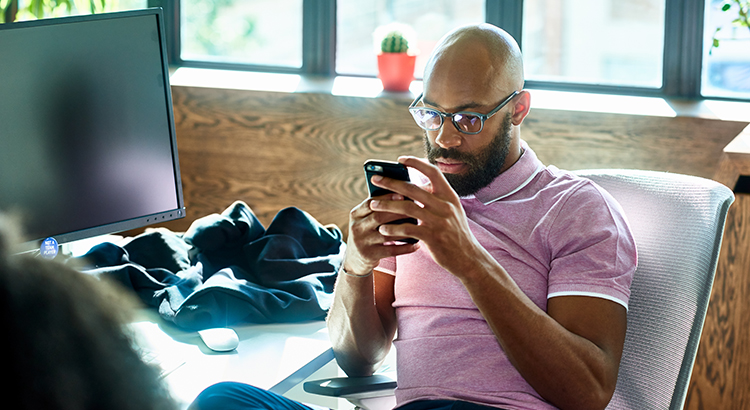 Mid adult man with beard and glasses texting in office